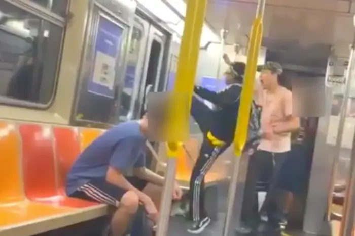 Image from video showing a person kicking out a subway window and another looking on in amazement
